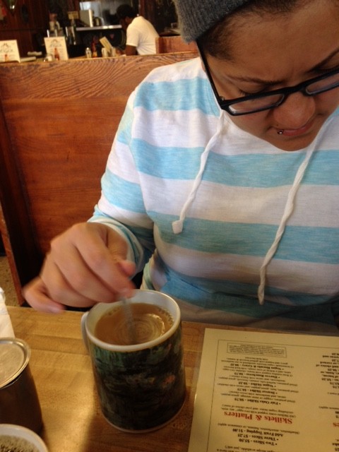 Gabby stirs her coffee