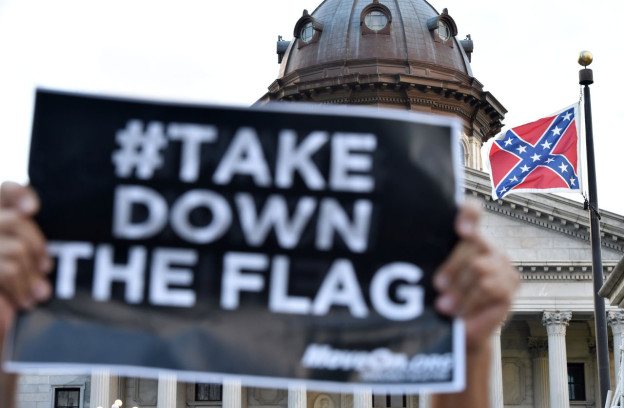 Hundreds of people protest against the Confederate flag (C) during a protest rally in Columbia, South, Carolina on June 20, 2015. The racially divisive Confederate battle flag flew at full-mast despite others flying at half-staff in South Carolina after the killing of nine black people in an historic African-American church in Charleston on June 17. Dylann Roof, the 21-year-old white male suspected of carrying out the Emanuel African Episcopal Methodist Church bloodbath, was one of many southern Americans who identified with the 13-star saltire in red, white and blue. AFP PHOTO/MLADEN ANTONOV (Photo credit should read MLADEN ANTONOV/AFP/Getty Images)