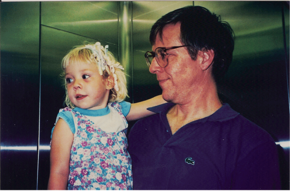 Rachel's dad holds her in an elevator. She is very young, pre-school age