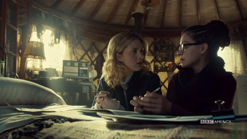 Delphine and Cosima kneel by the bed to talk science