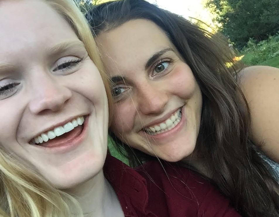 Lindy and Nicole smile at each other adorably in the park.