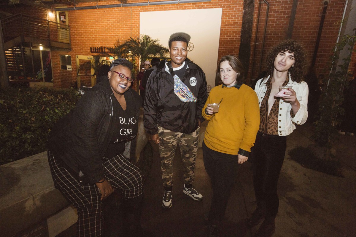 Four people pose for a photo outside.