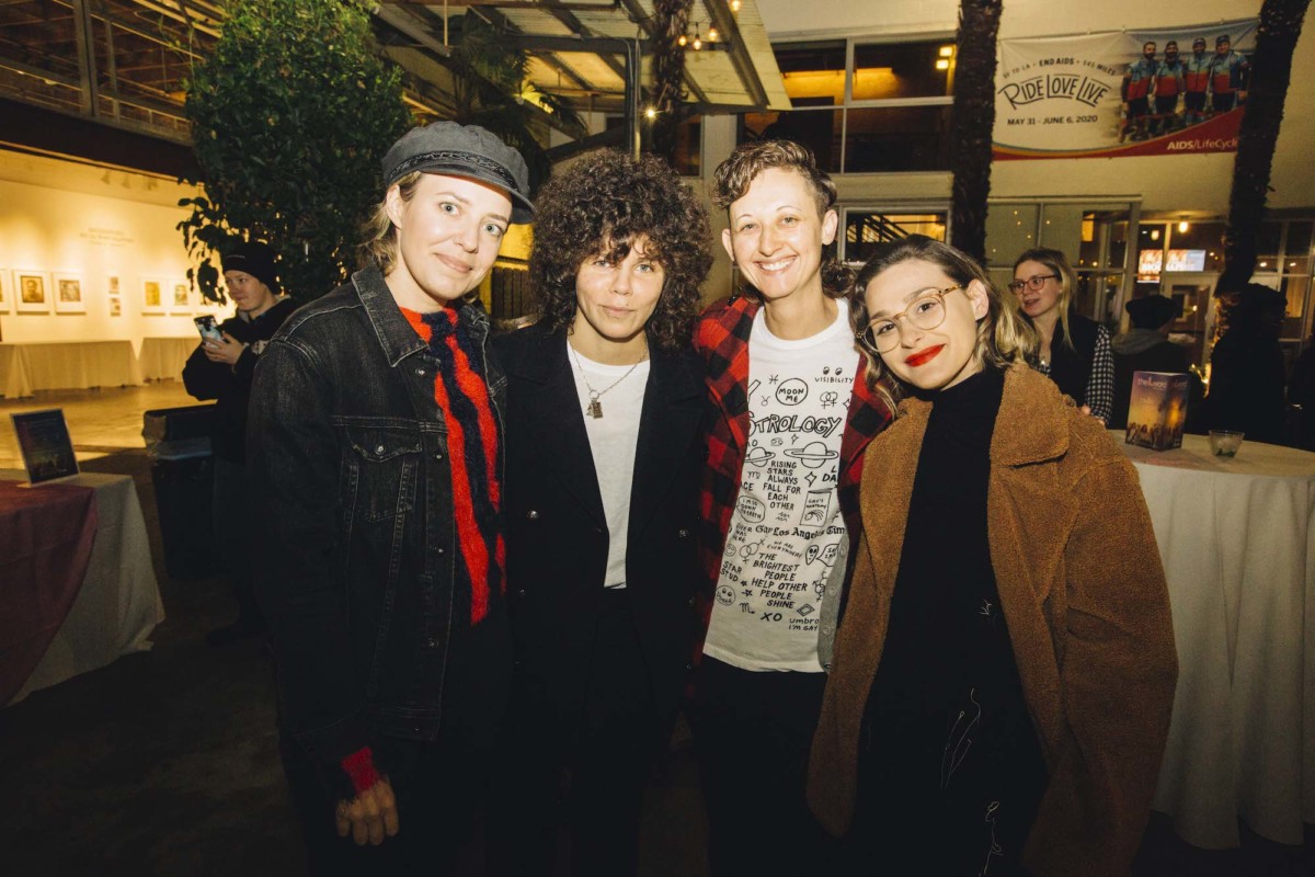Four people pose for a photo inside at a party reception area.