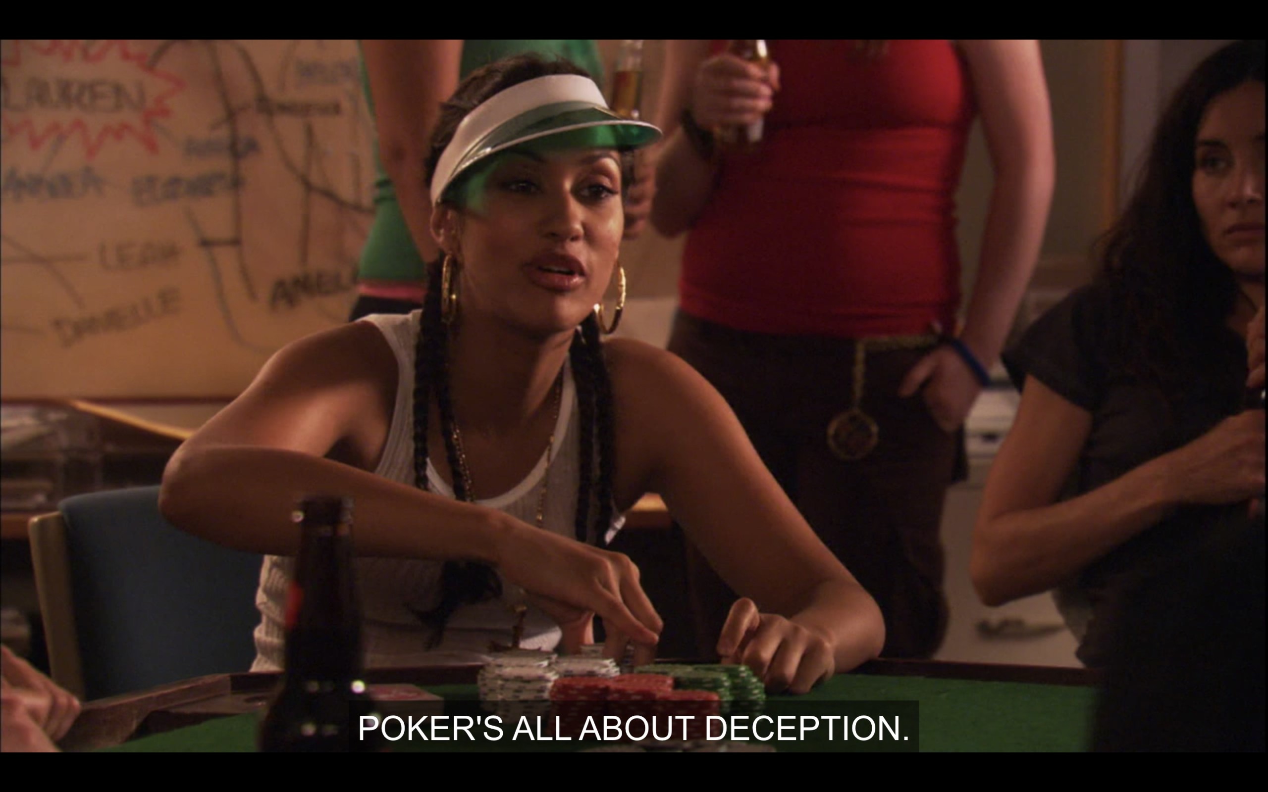 Papi is in a white tank top and a green poker visor, sitting at a poker table with a stack of poker chips in front of her. She says, "Poker's all about deception."