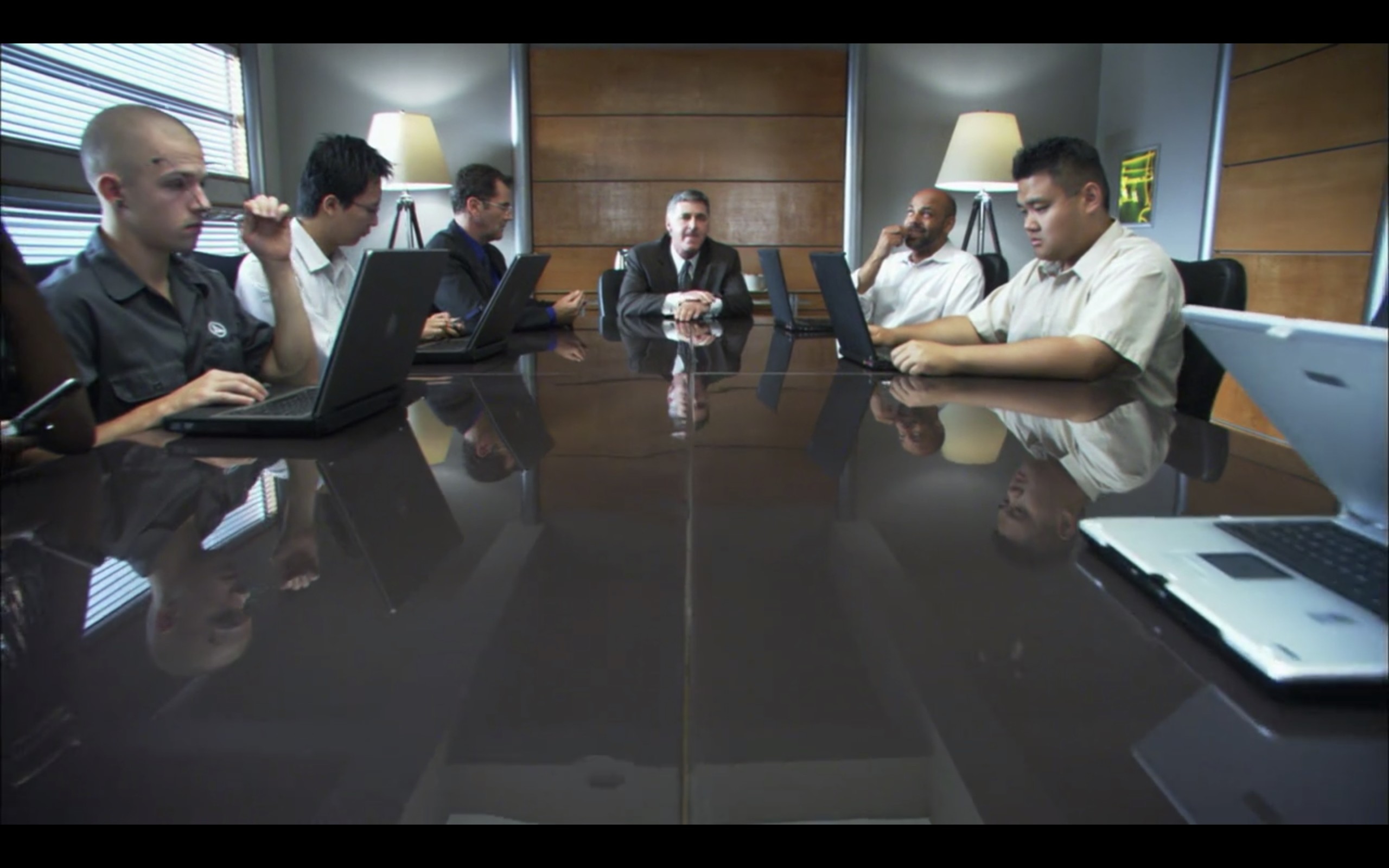 Board room table of tech dudes on their laptops. 