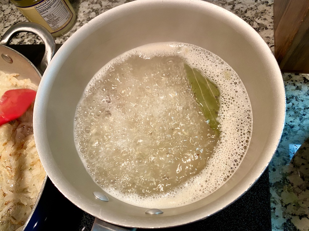 a pot of rice with a roiling boil and a little peek of bay leaf visible through the bubbles