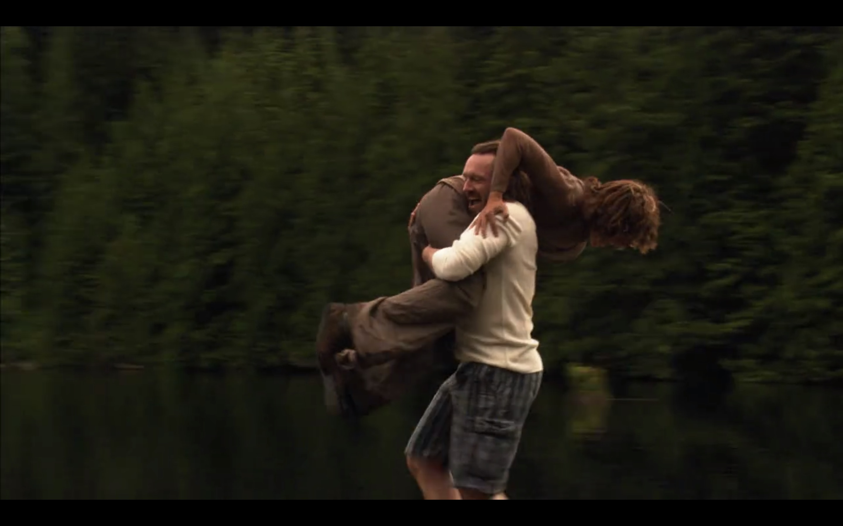 A terrible man carries Bette on his shoulder, about to throw her into the lake