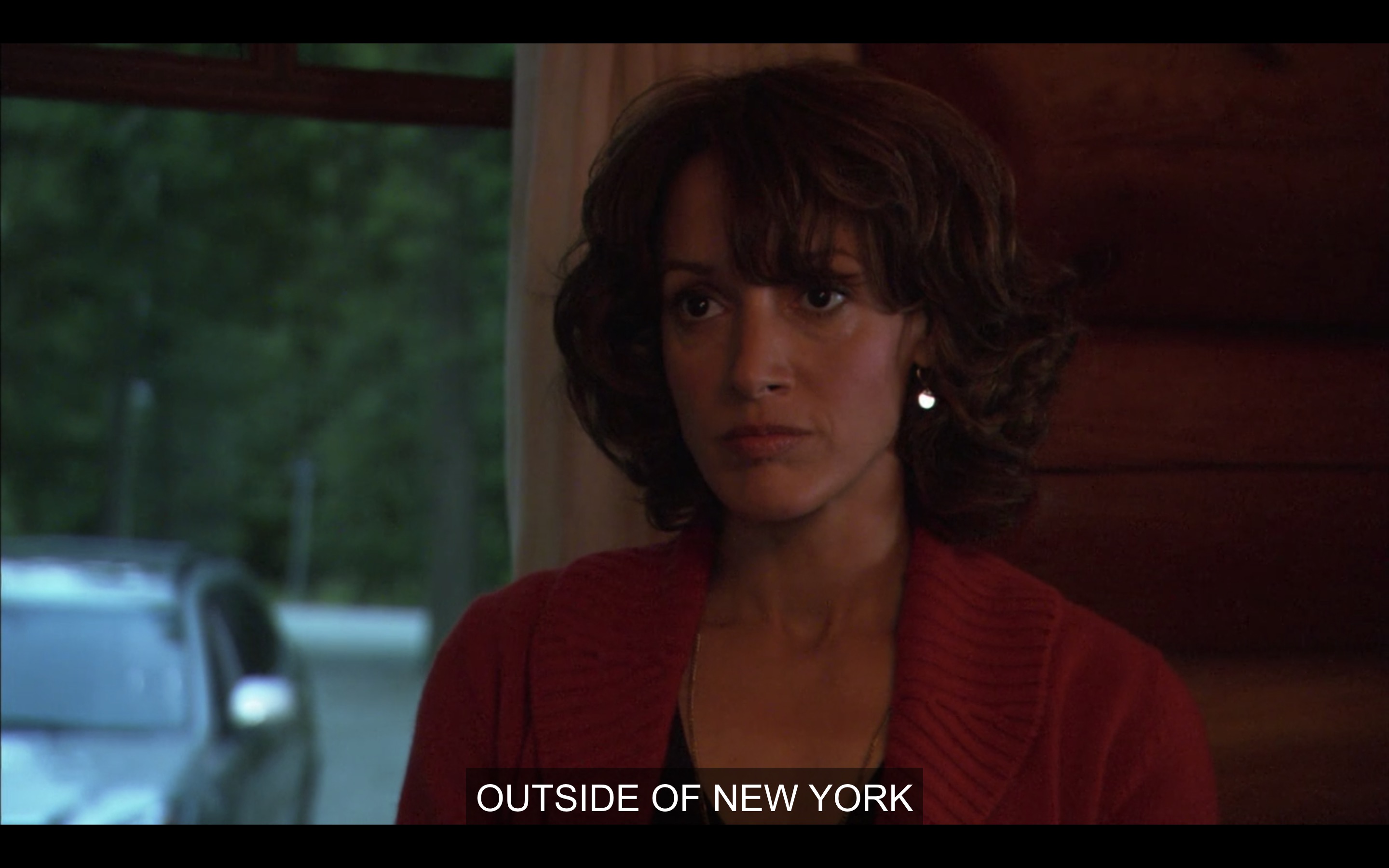 Bette in a red cardigan looking at a man and she is not happy about this man