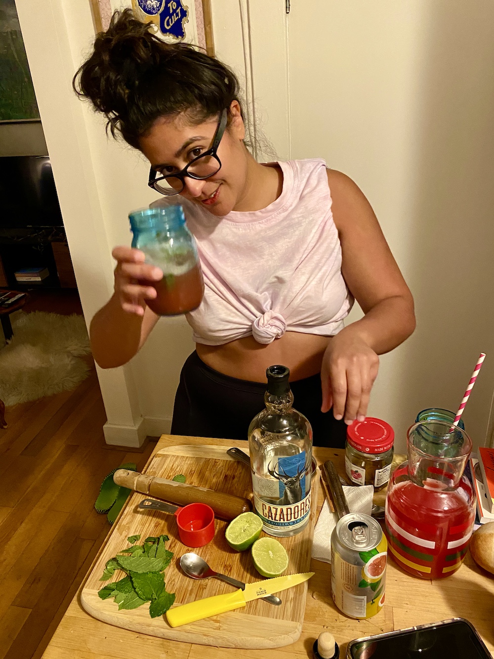 sarah raises a blue glass jar for a toast, with a pink watermelon cocktail inside