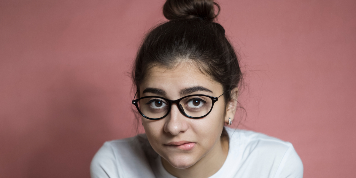 A troubled-looking girl biting her lip as she looks at the camera