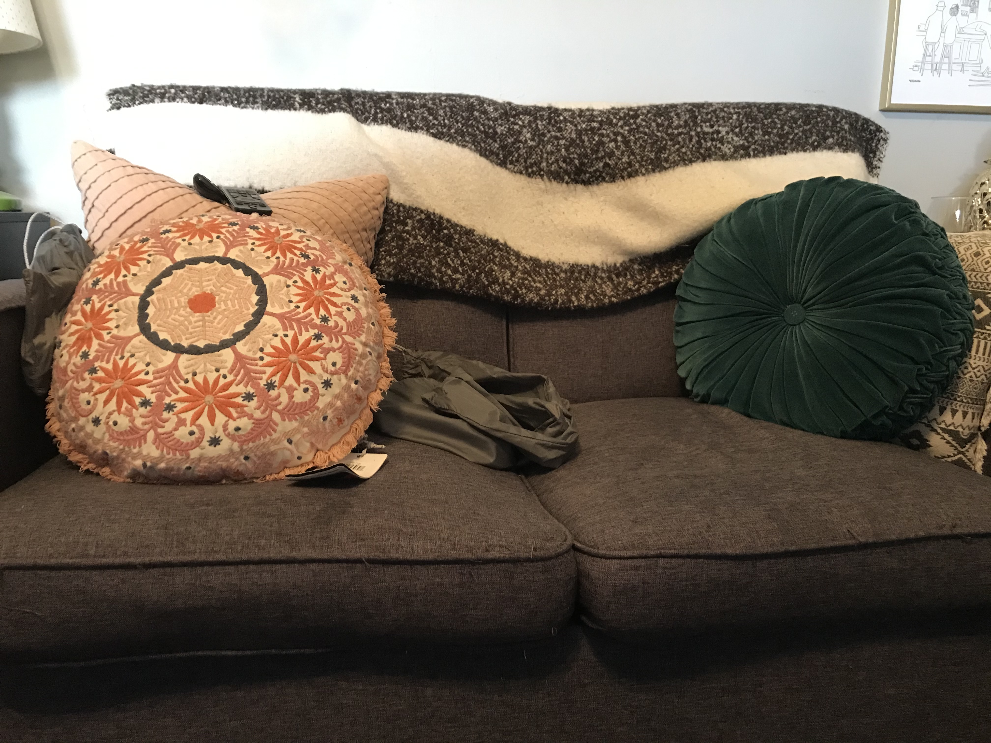 A brown couch with a blanket and a few throw pillows.