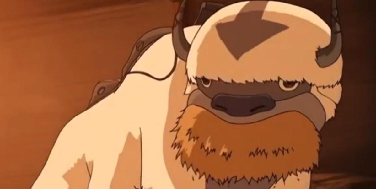 a bison with an arrow on his head has his mouth stuffed full of hay