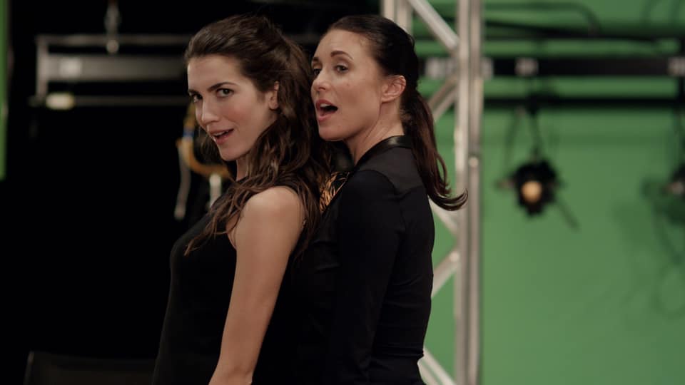 The two leads of Liberty's Secret dance and sing in a green room.