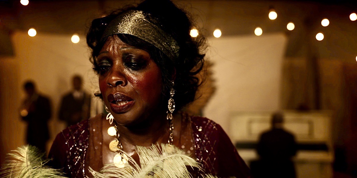 Viola Davis as Ma Rainey, in a gold headdress and a feather boa on stage. This is a still from Netflix's 