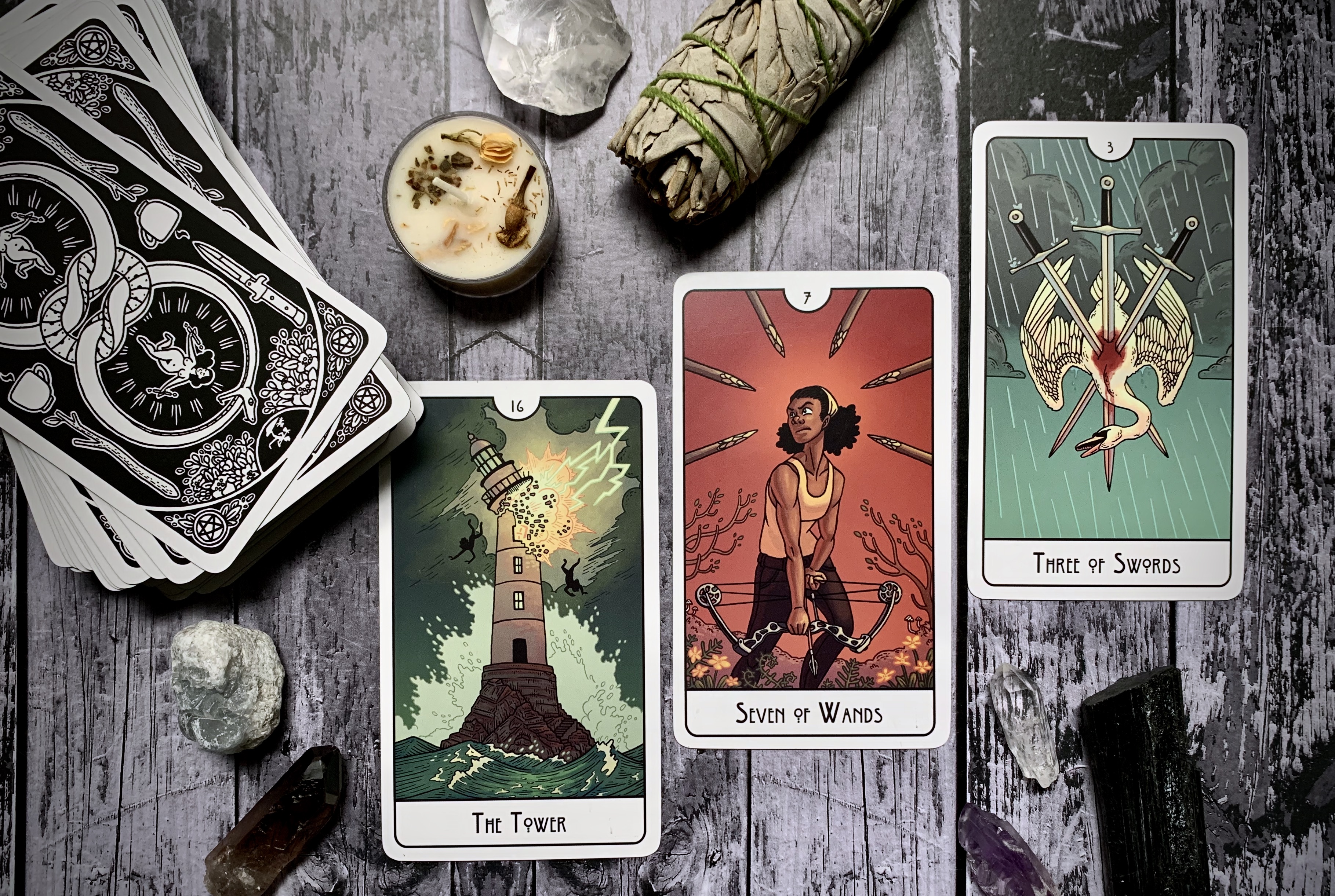 This image contains three cards. The Tower card depicts a lighthouse being hit by a lightning strike. Two figures tumble from it toward the surrounding water. The Seven of Wands depicts a person with a determined, sort of ready-to-fight look on their face who is holding a bow and arrow facing downward. Six more arrows point at them from all sides. Finally, the three of swords shows a swan, falling head first against a rainy sky. Three swords pierce the heart of the swan. Blood is visible against the white feathers.
