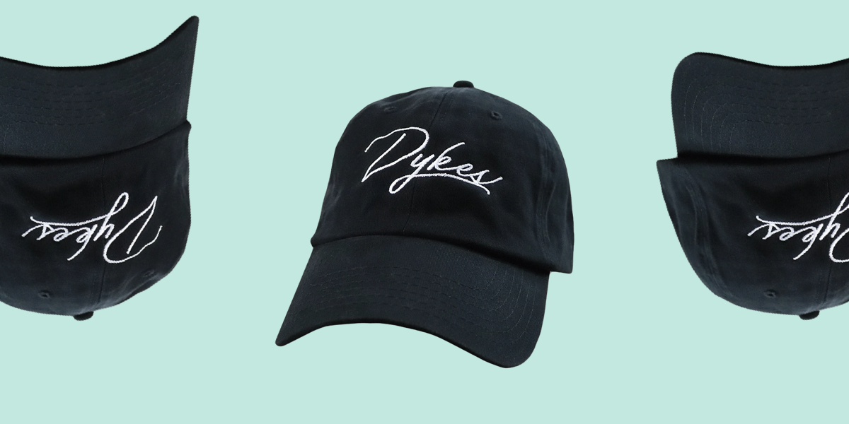 A black baseball cap with black stitching. In white embroidery the word "Dykes" loops elegantly on the front.