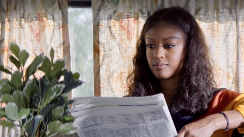 Ryan Wilder reads a newspaper in her RV van — that is also her home — while sitting next to her beloved plant.