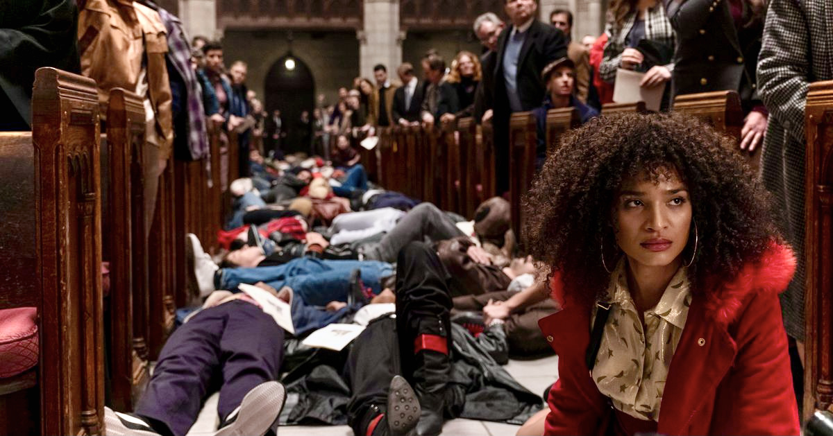 In a still from the television show Pose, Indya Moore sits on the floor of St. Peter's Cathedral during a staged "die in" during the early 1990s of HIV/AIDS Activism