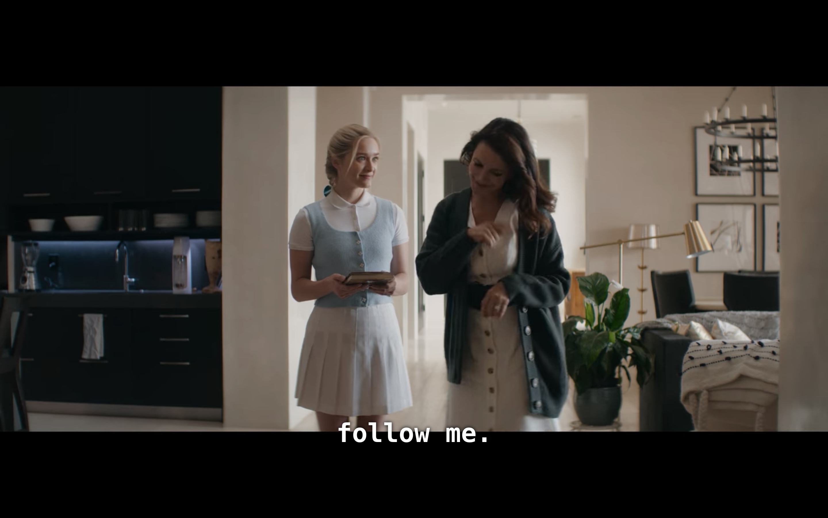 in Mary's house, Mary telling Grace (in a white tennis skirt, white polo and blue sweater-vest) to follow her