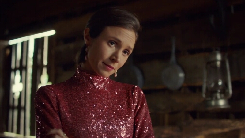 Waverly, wearing a pink glittery mock turtleneck, tilts her head as she regards off-screen Wynonna with a loving but worried look.
