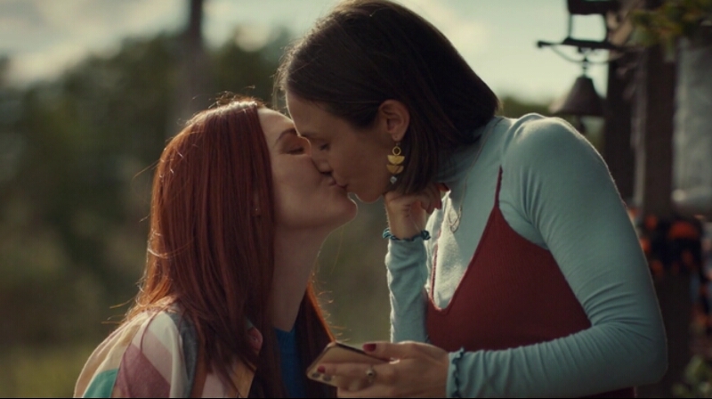Waverly Earp, on the top step of the porch, leans down to kiss Nicole who is standing at the bottom.