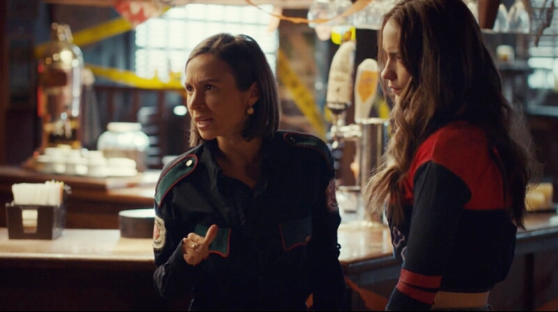Waverly is dressed Nicole's too-big cop uniform and authoritatively pointing her thumb back at herself.
