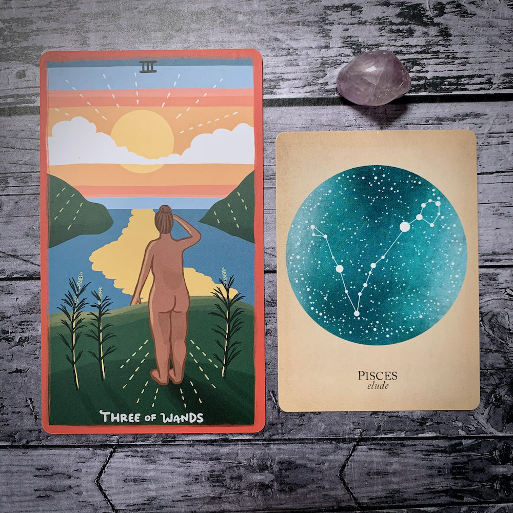A photo of the tarot card for Three of Wands and the astrological card representing Pisces, along with a small crystal