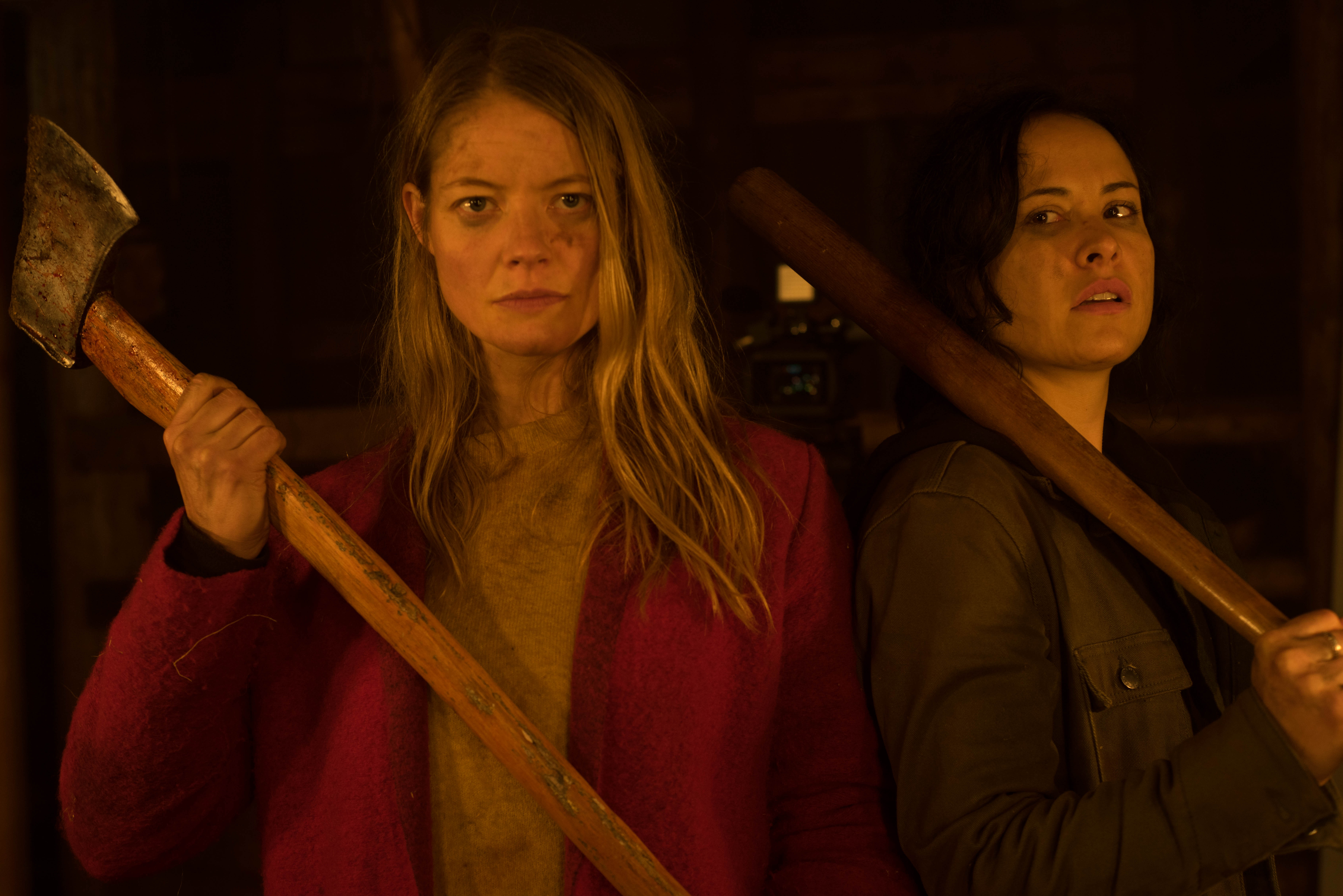 Valerie and Renee stand bloody and ready to fight each holding an axe