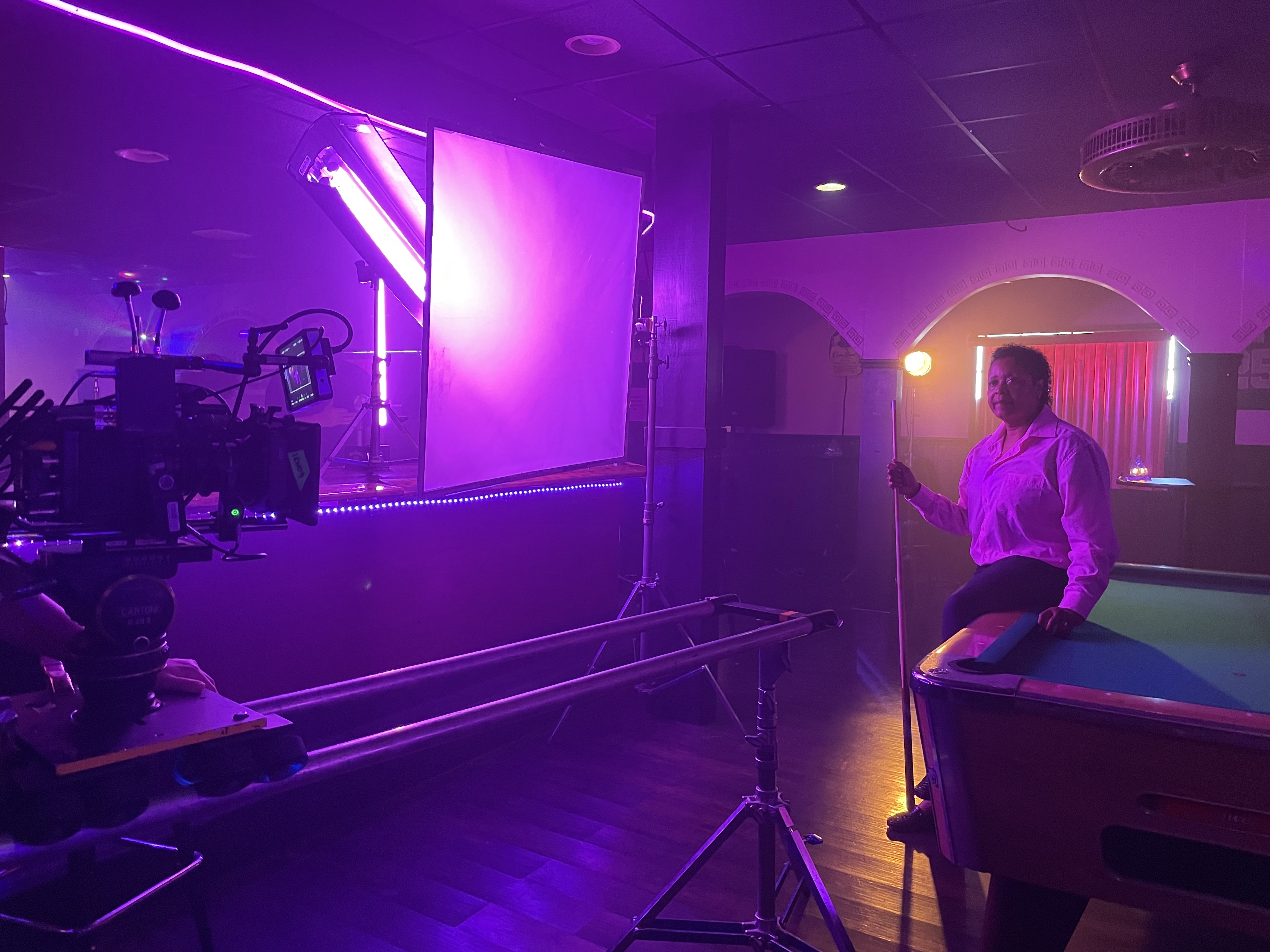 Sheila Smallman, owner of Herz lesbian bar in Alabama, sits on a pool table while being filmed for The Lesbian Bar Project