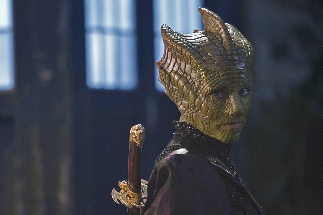 Madame Vastra from Dr Who, a Salurian alien with green lizard-like skin, looking badass with a sword on her back