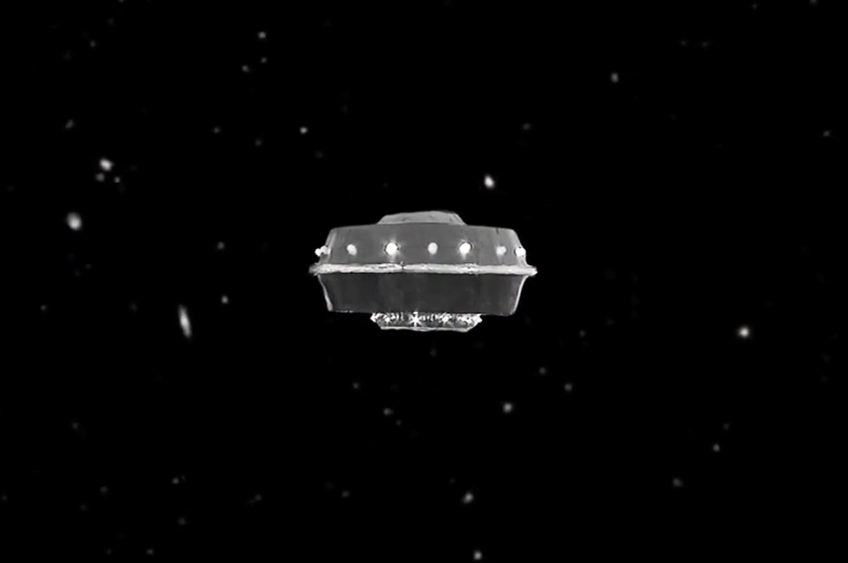 A hokey spaceship that looks like it was made out of a tin can hovering against a black starry backdrop