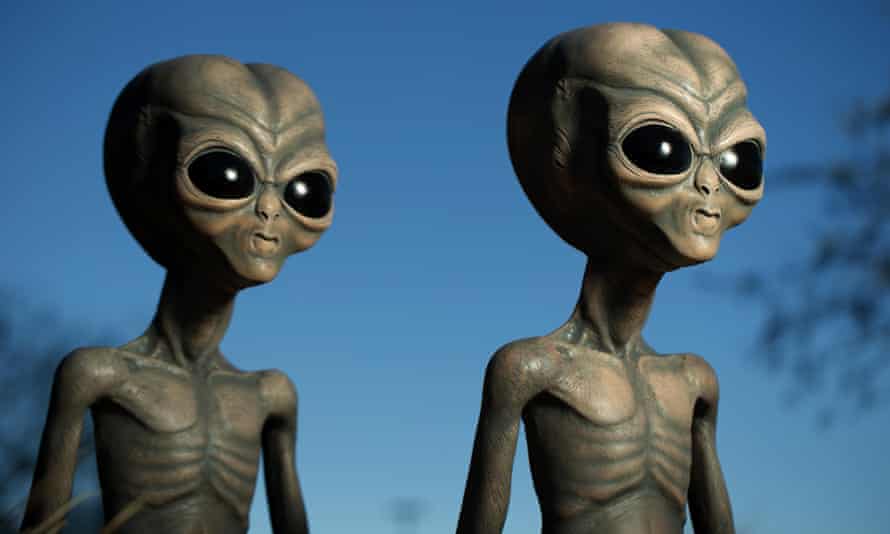 Two classic green-grey skinned aliens with skinny bodies and oversized heads and eyes