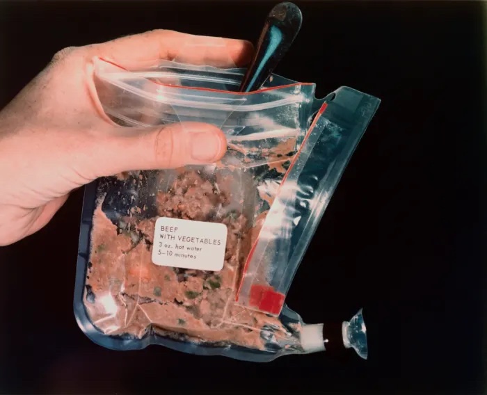 An open plastic package of dehydrated brown food with the label BEEF WITH VEGETABLES