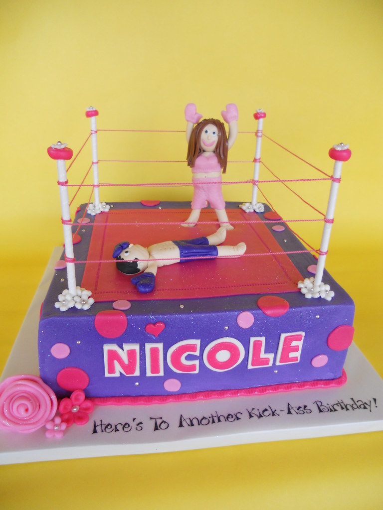 a cake that says nicole with a triumphant woman in a boxing ring having knocked out her opponent