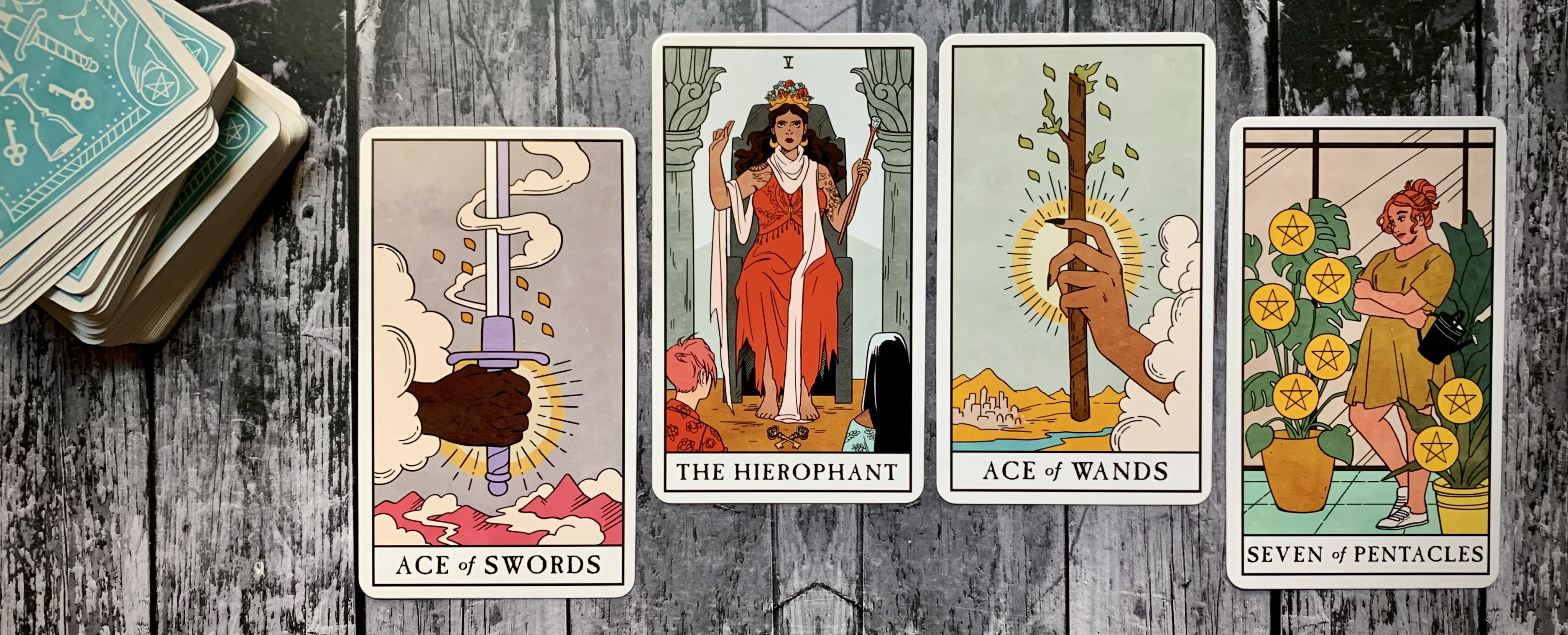 A spread of four tarot cards - the Ace of Swords, the Hierophant, Ace of Wands, and Seven of Pentacles - spread out against a wooden background