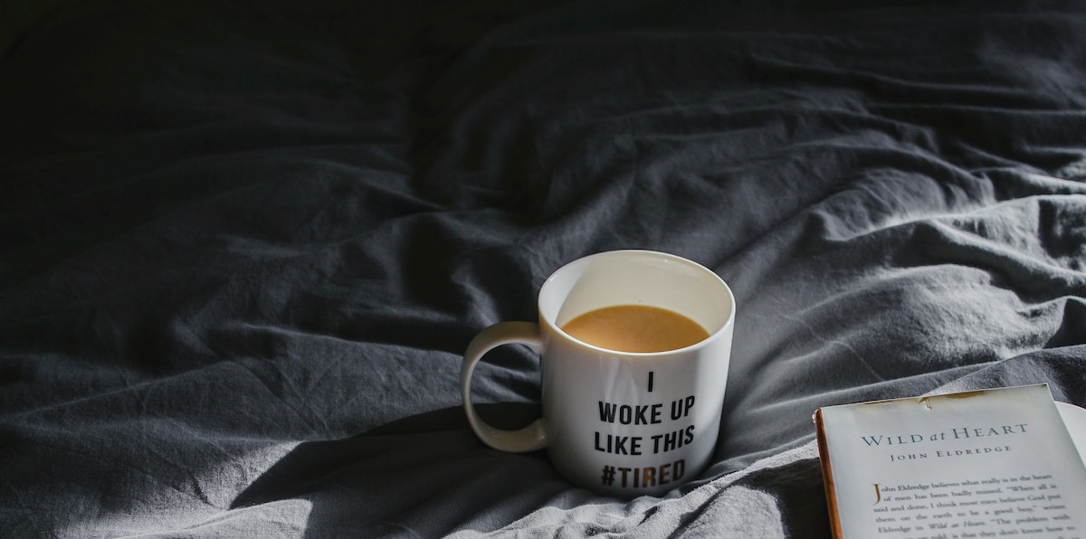 A dramatically lit photo of a cup of coffee in a mug that reads 