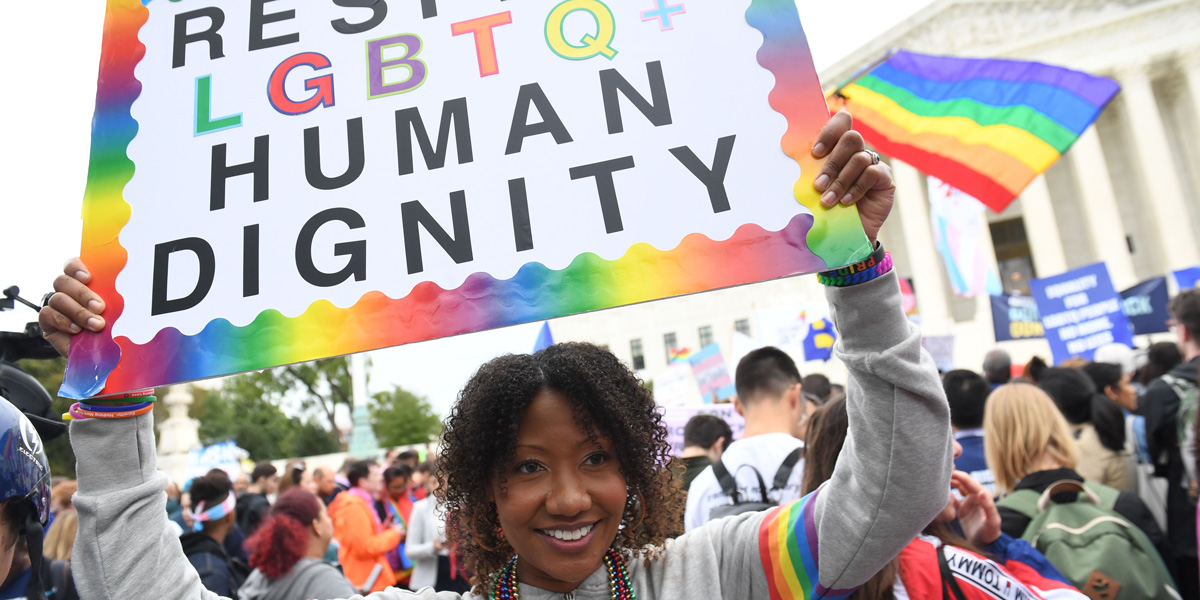 Demonstrators in favour of LGBT rights rally outside the US Supreme Court in Washington, DC, October 8, 2019, as the Court holds oral arguments in three cases dealing with workplace discrimination based on sexual orientation. A black woman holds a sign that says 