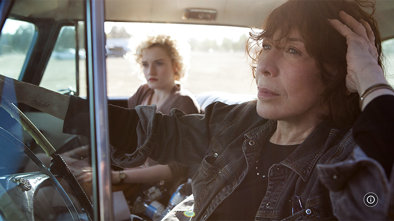 Elle and Sage ride together in a car with the windows down on a sunny afternoon