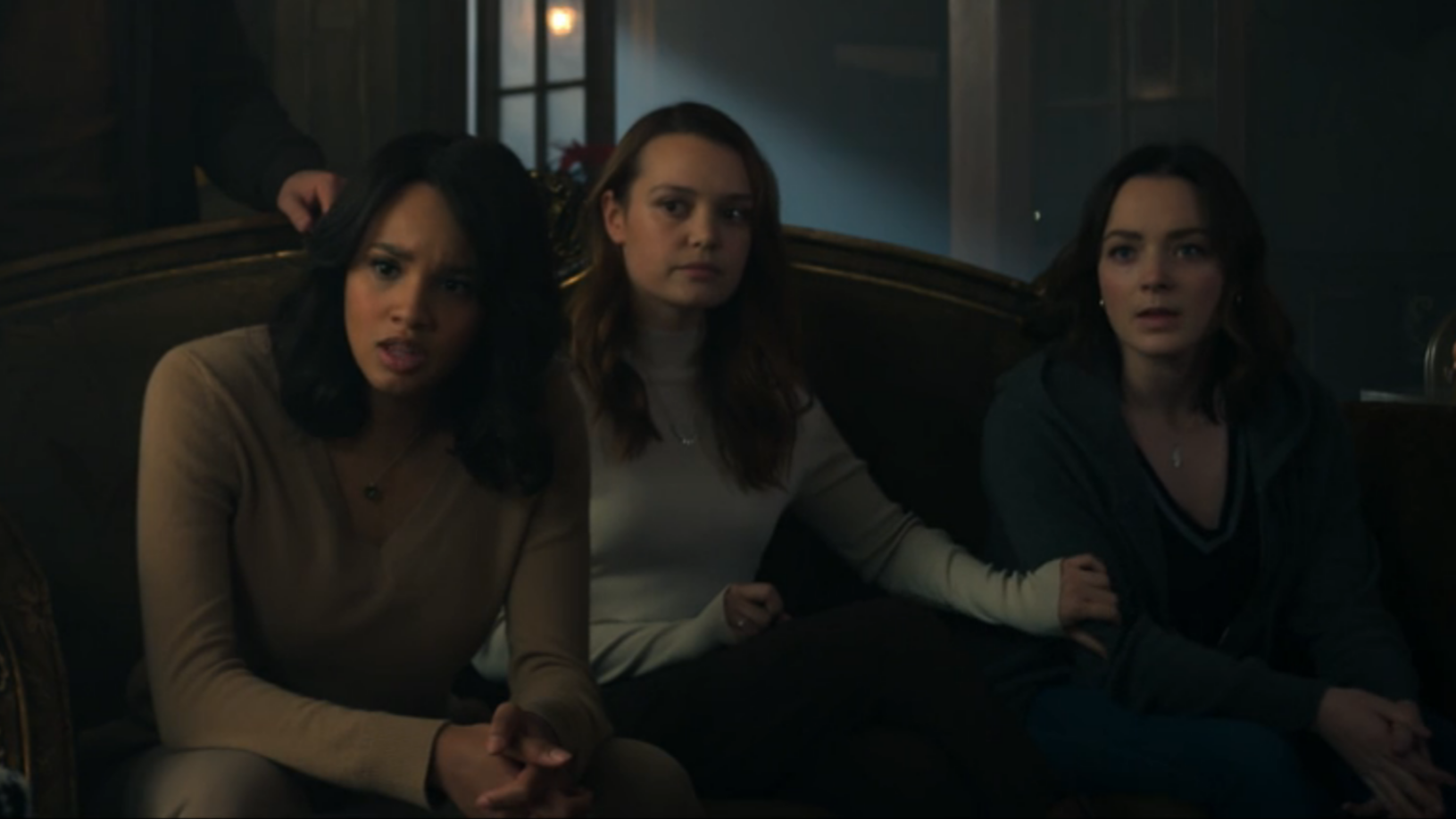 Abigail, Tally, and Scylla sit on the couch and look pissed; Tally has a hand on Scylla's arm