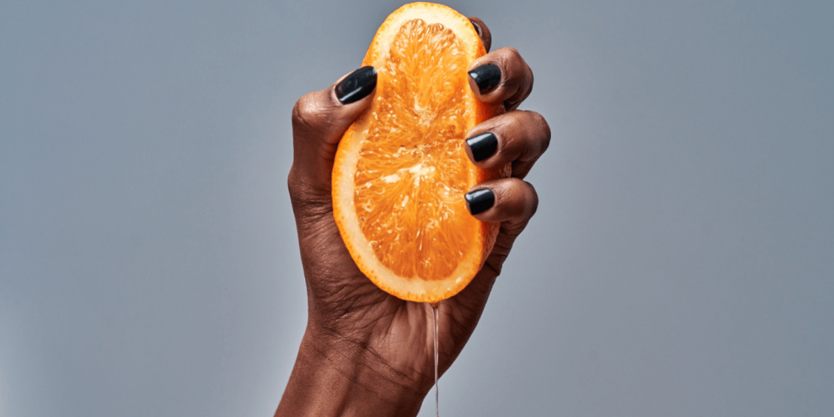 an orange being squeezed with a hand