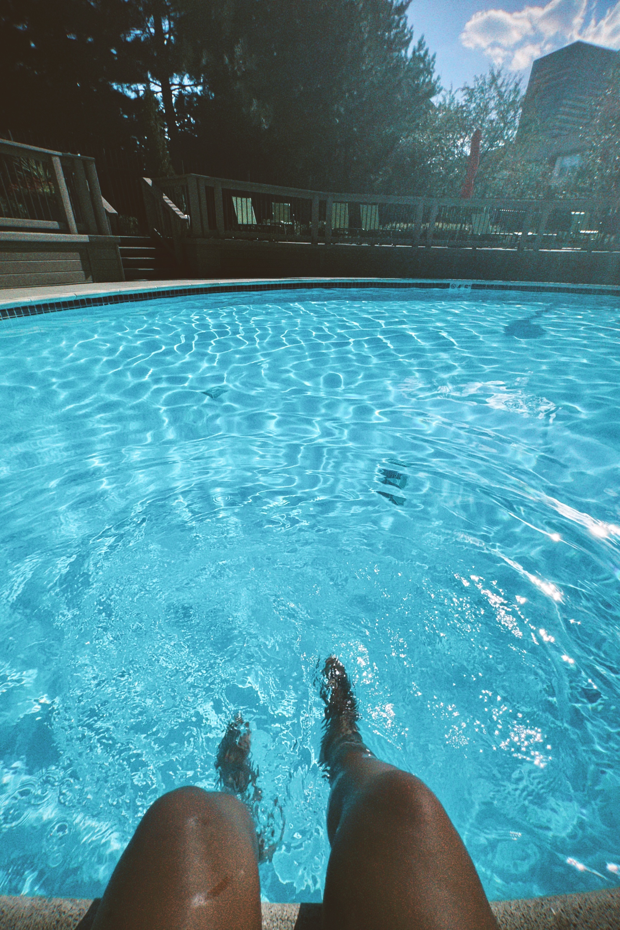 a photo taken from Carmen's perspective of her legs splashing in a pool