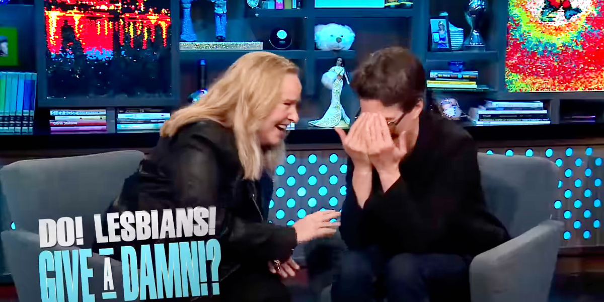 Rachel Maddow and Melissa Etheridge laugh together while sitting close in chairs on Andy Cohen's set for 