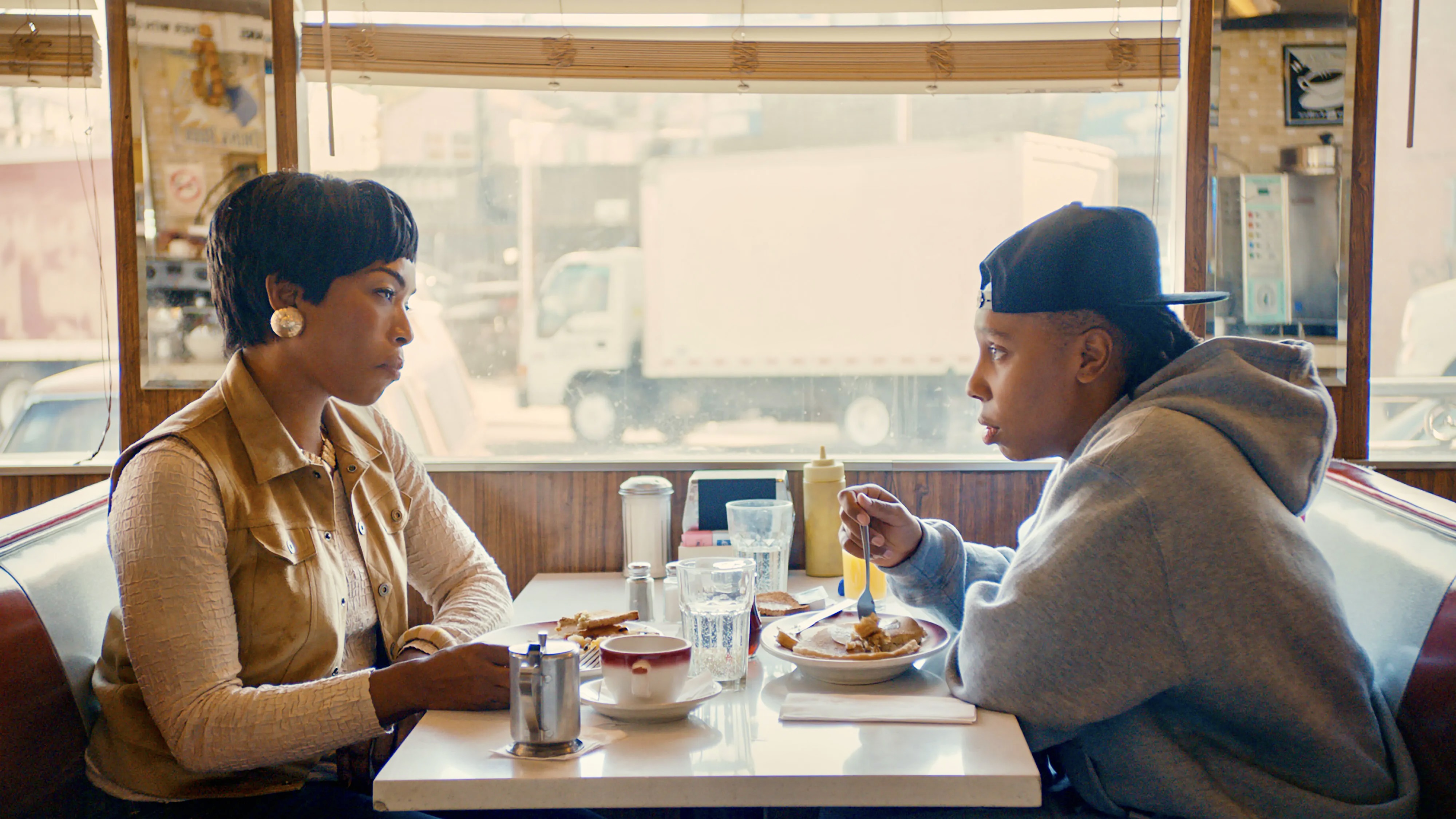 Denise (Lena Waithe) and her mother (Angela Bassett) share breakfast at a diner, they are backlit by the sun