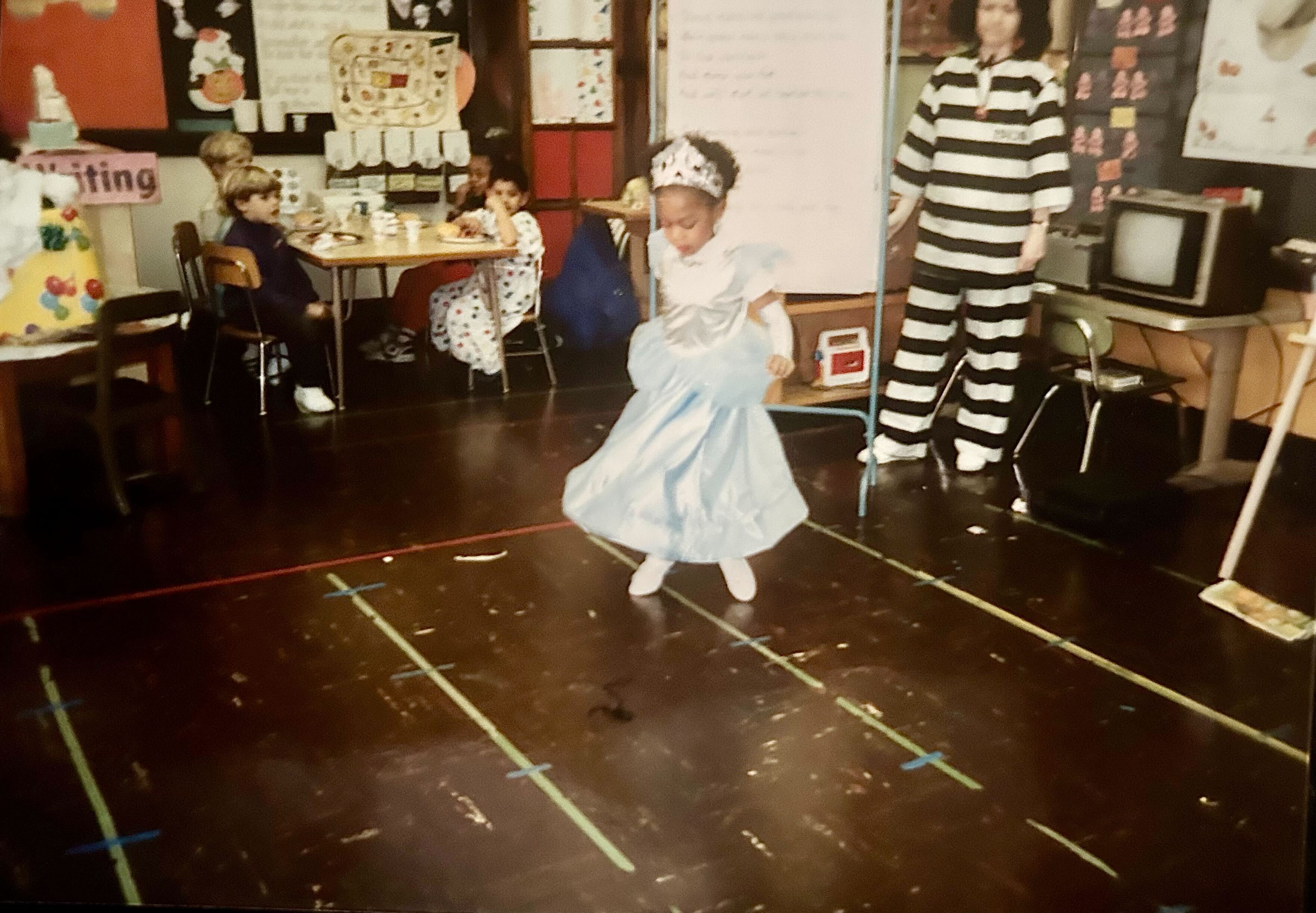 Halloween in the early 90s and Carmen is wearing a Cinderella dress in Kindergarten.