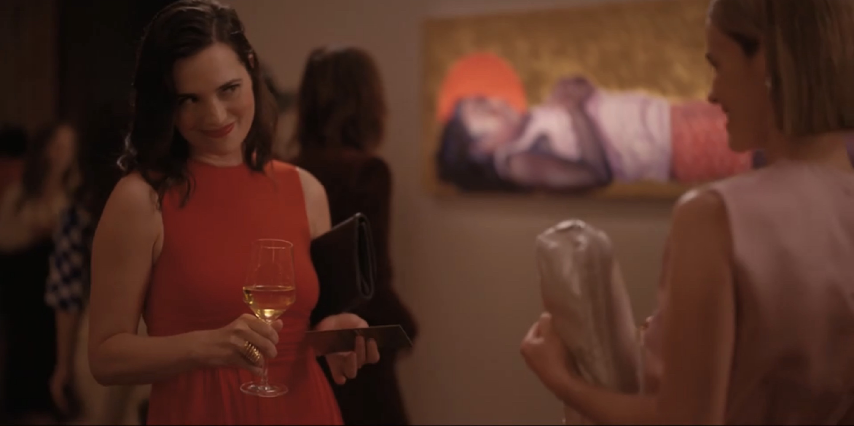 Asia in a red dress with glass of wine looking at Alice flirtatiously