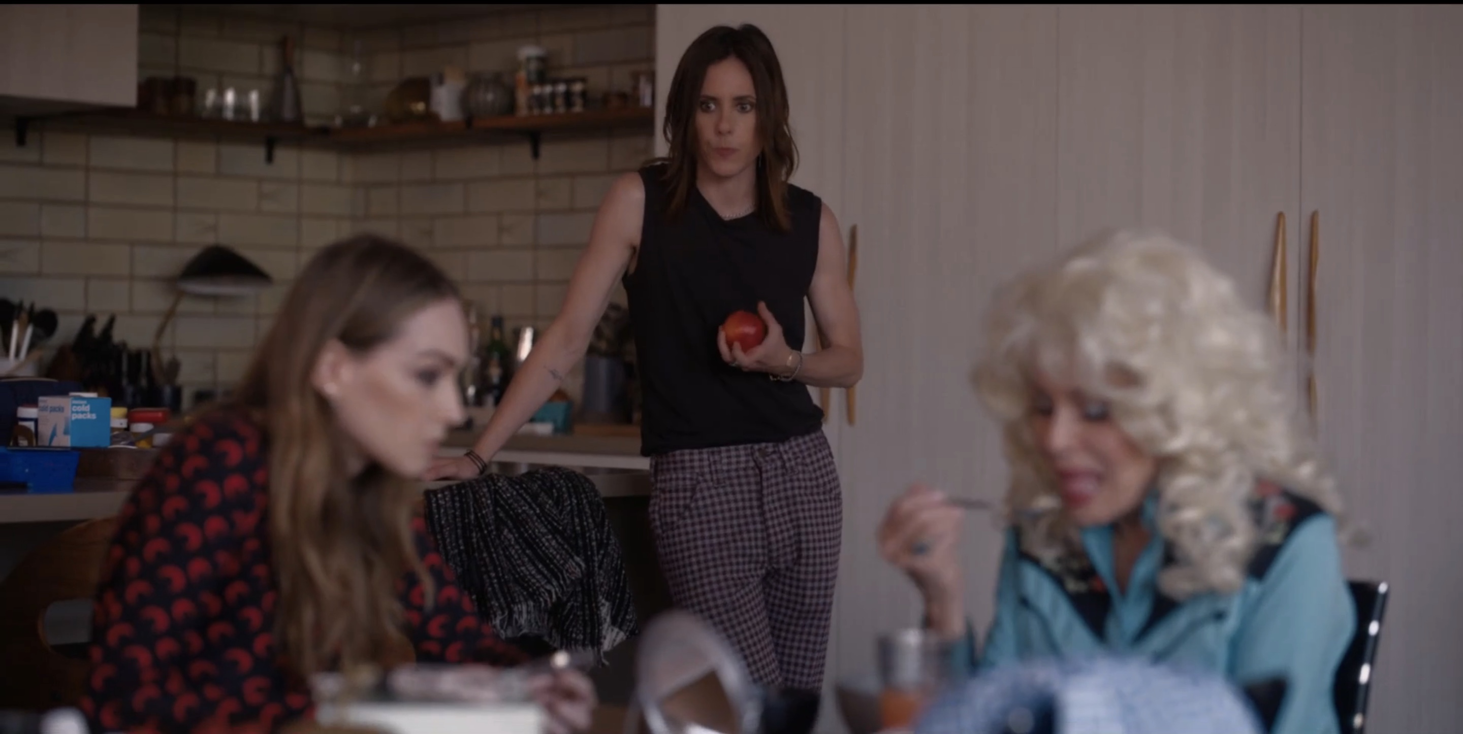 Shane holding an apple watching Tess and Patty at the table