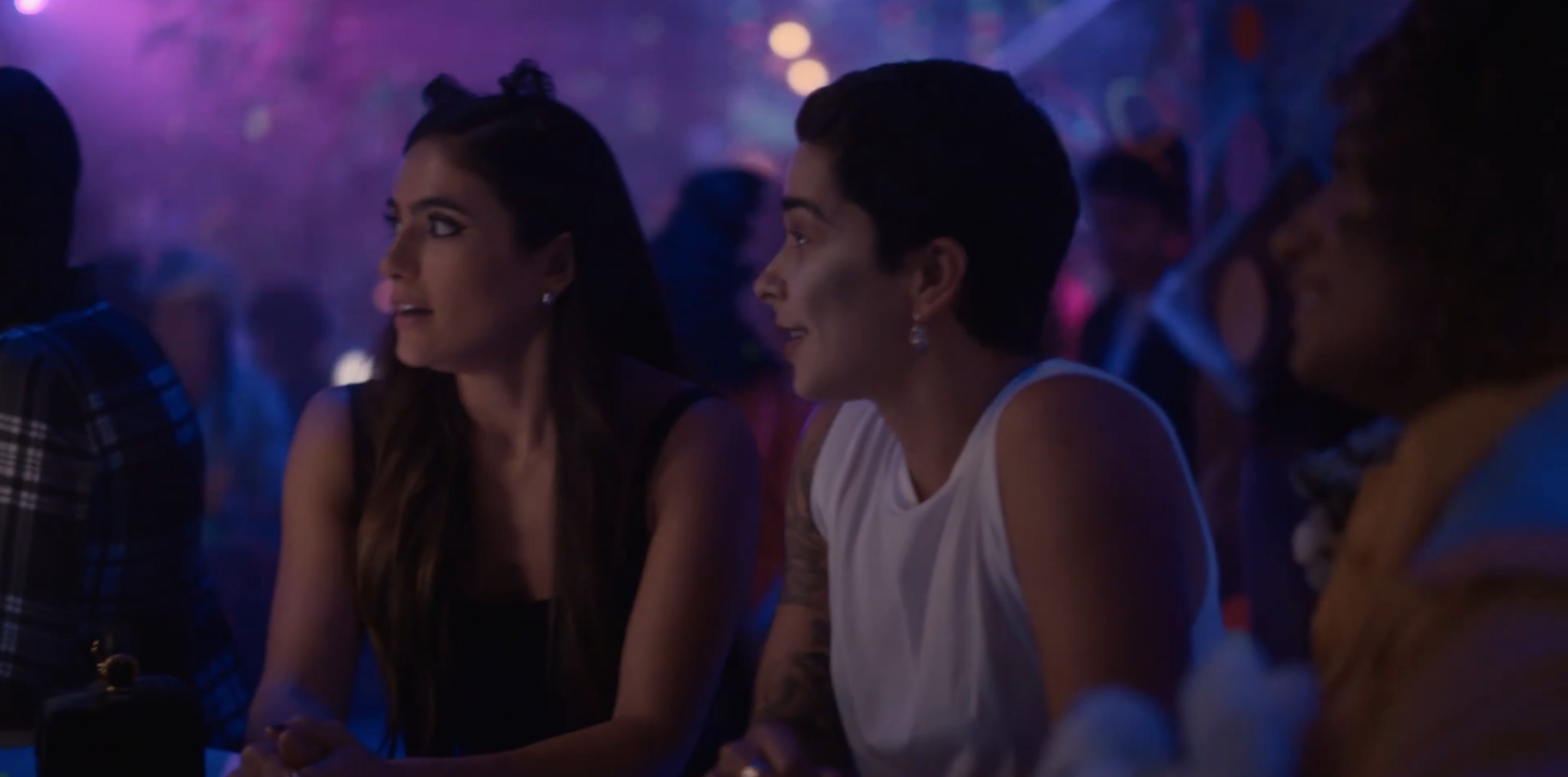 Dani and Roxy at the bar in their costumes looking at Shane