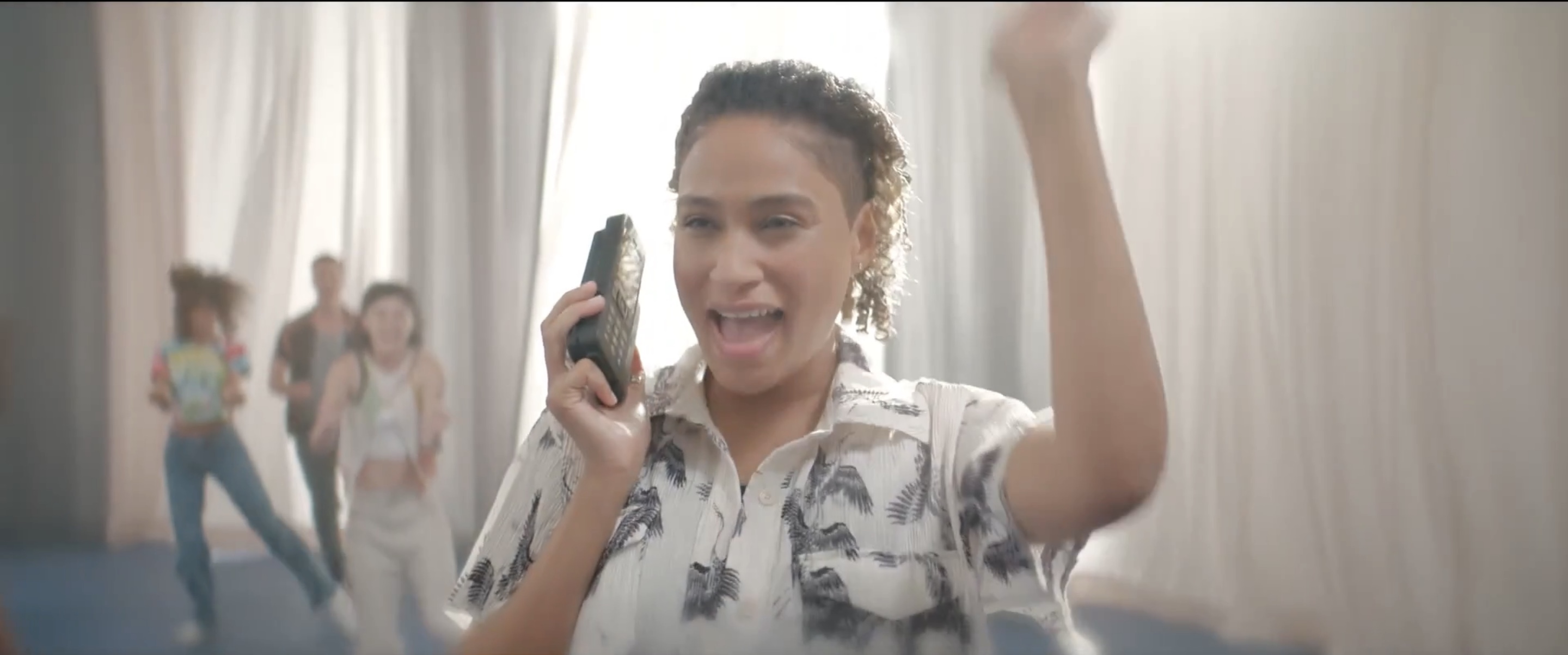Sophie on a vintage cell phone doing a fist bump
