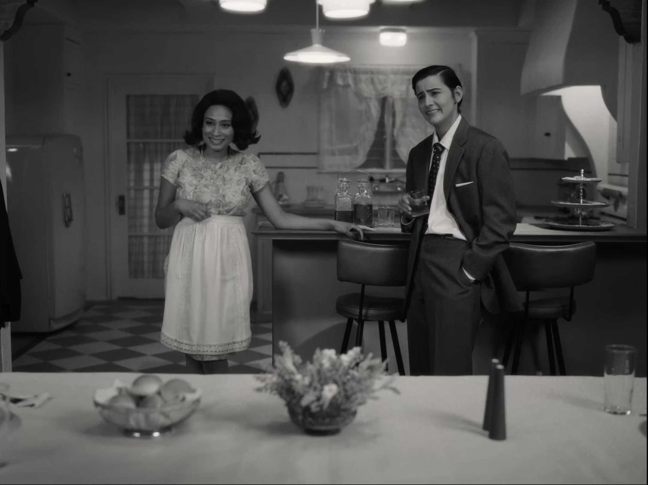 Finley in her suit and Sophie in her dress standing behind dinner table smiling