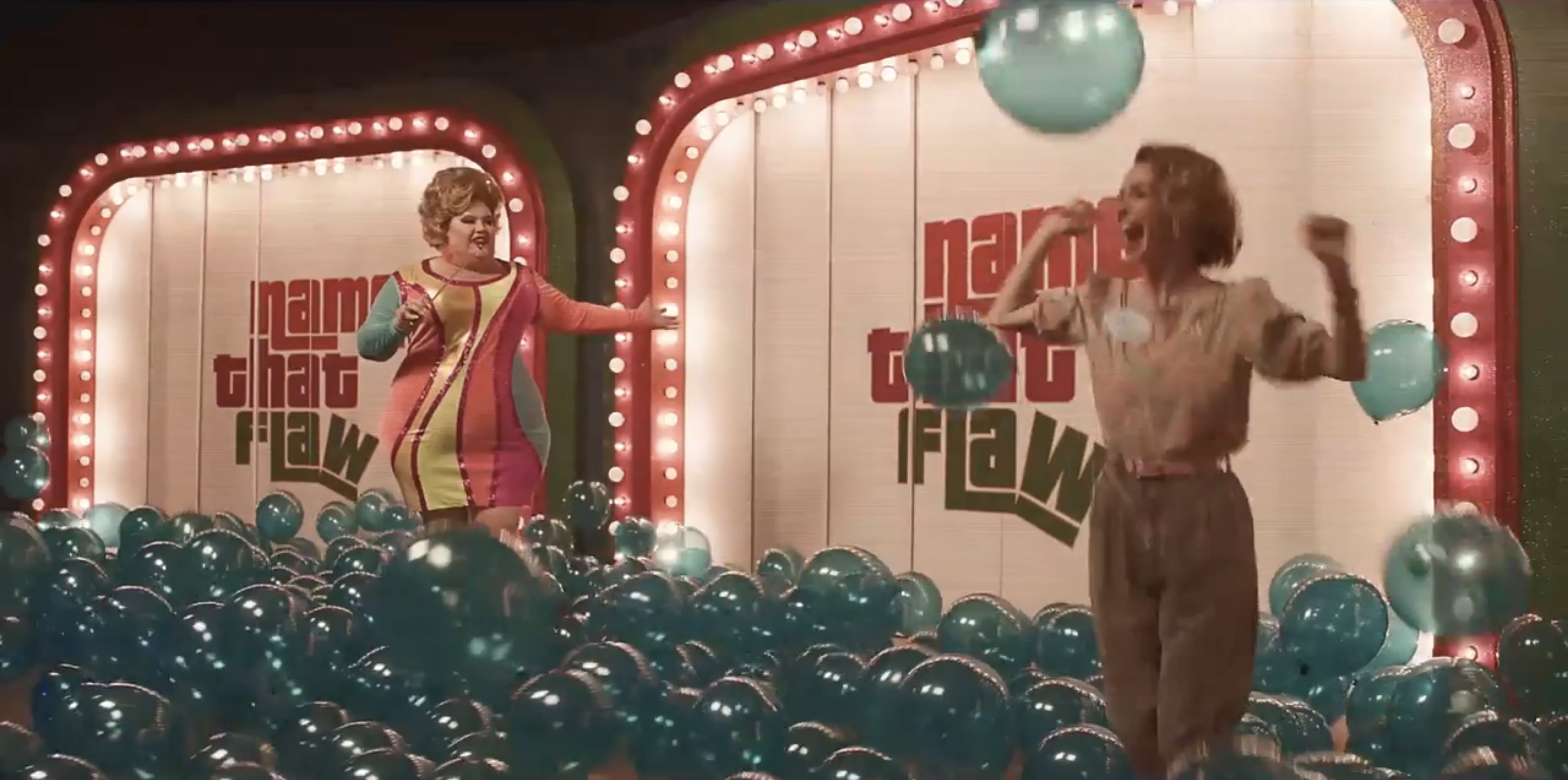 Drag queen screaming as Alice delights in a bunch of blue balloons